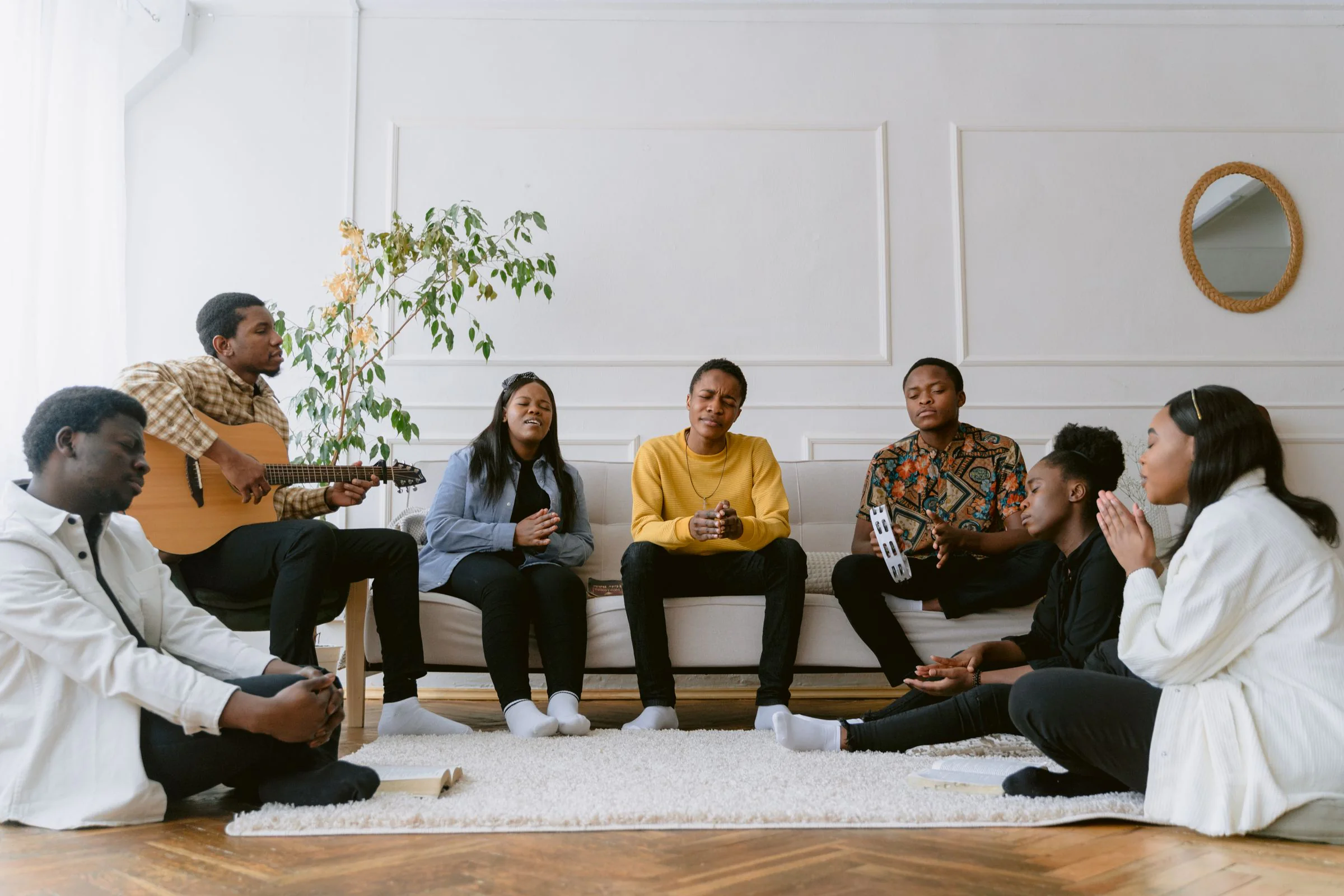 Young adults singing and praying together in a home