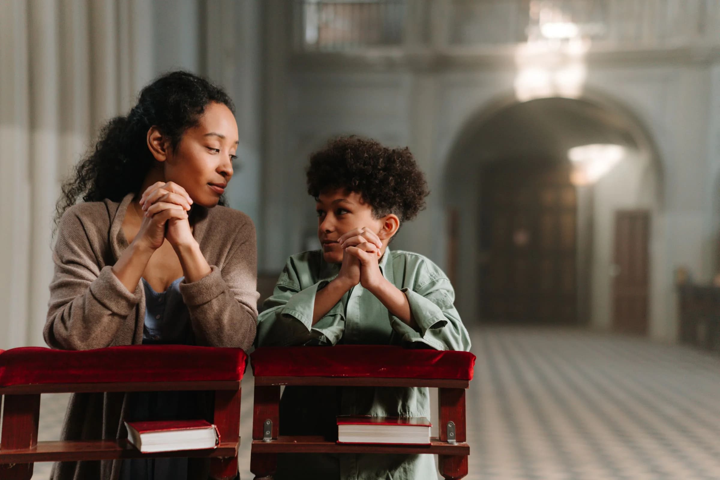 A mother and son praying together inside a church